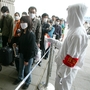 A railway worker wearing protective clothing to ward off the SARS virus controls a line of travelers as they wait to enter Beijing's West Railway Station Tuesday in 2003.