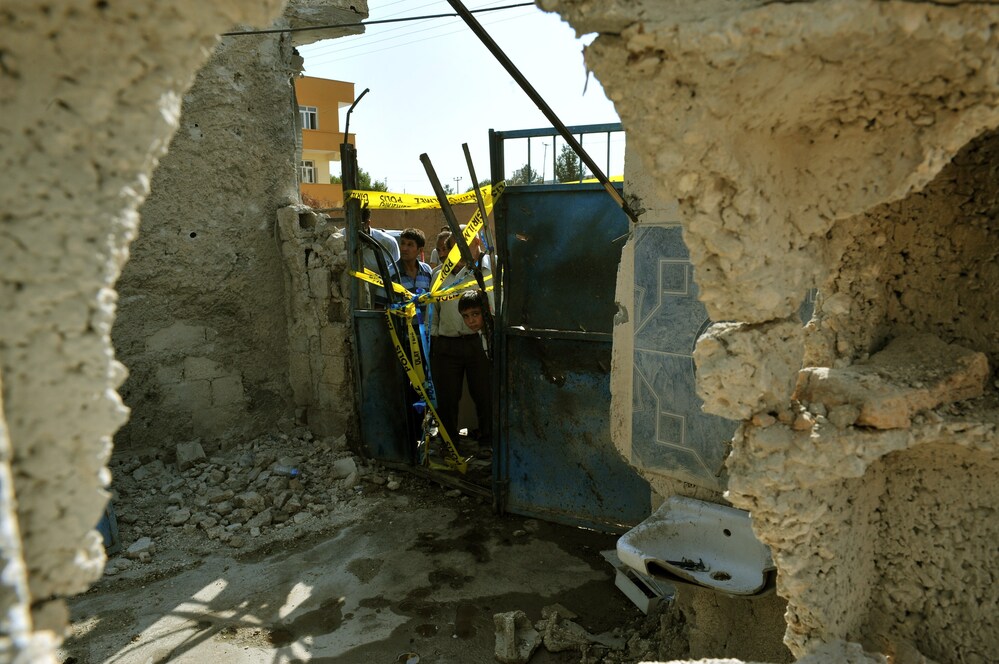 Local residents check on the damaged house where five Turkish civilians were killed on October 3 by a mortar bomb in the southern border town of Akcakale.