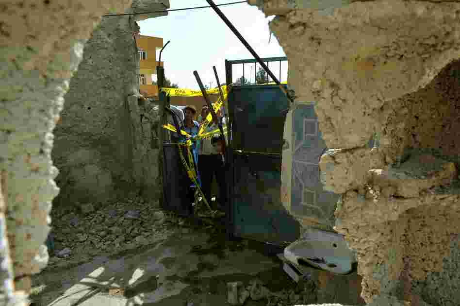 Local residents check on the damaged house where five Turkish civilians were killed on October 3 by a mortar bomb in the southern border town of Akcakale.