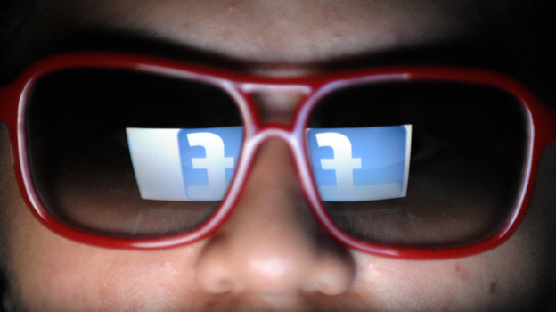 Does he need to watch what he likes? Facebook's logo is reflected in the glasses of a student in Manila.