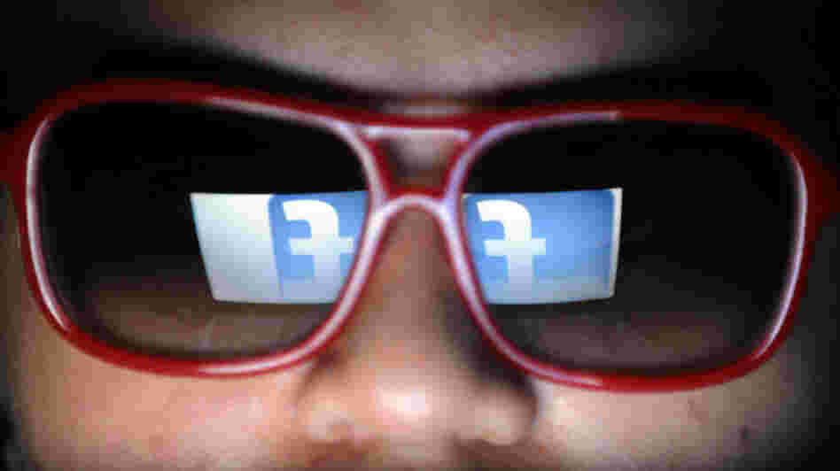 Does he need to watch what he likes? Facebook's logo is reflected in the glasses of a student in Manila.