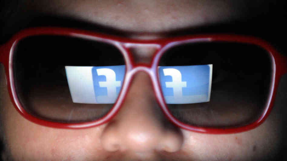 Does he need to watch what he likes? Facebook's logo is reflected in the glasses of a student in Manila.