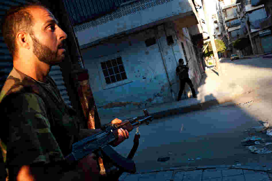 Free Syrian Army fighters take cover from helicopter fire in the Bustan Pasha neighborhood of Aleppo, Aug. 21.