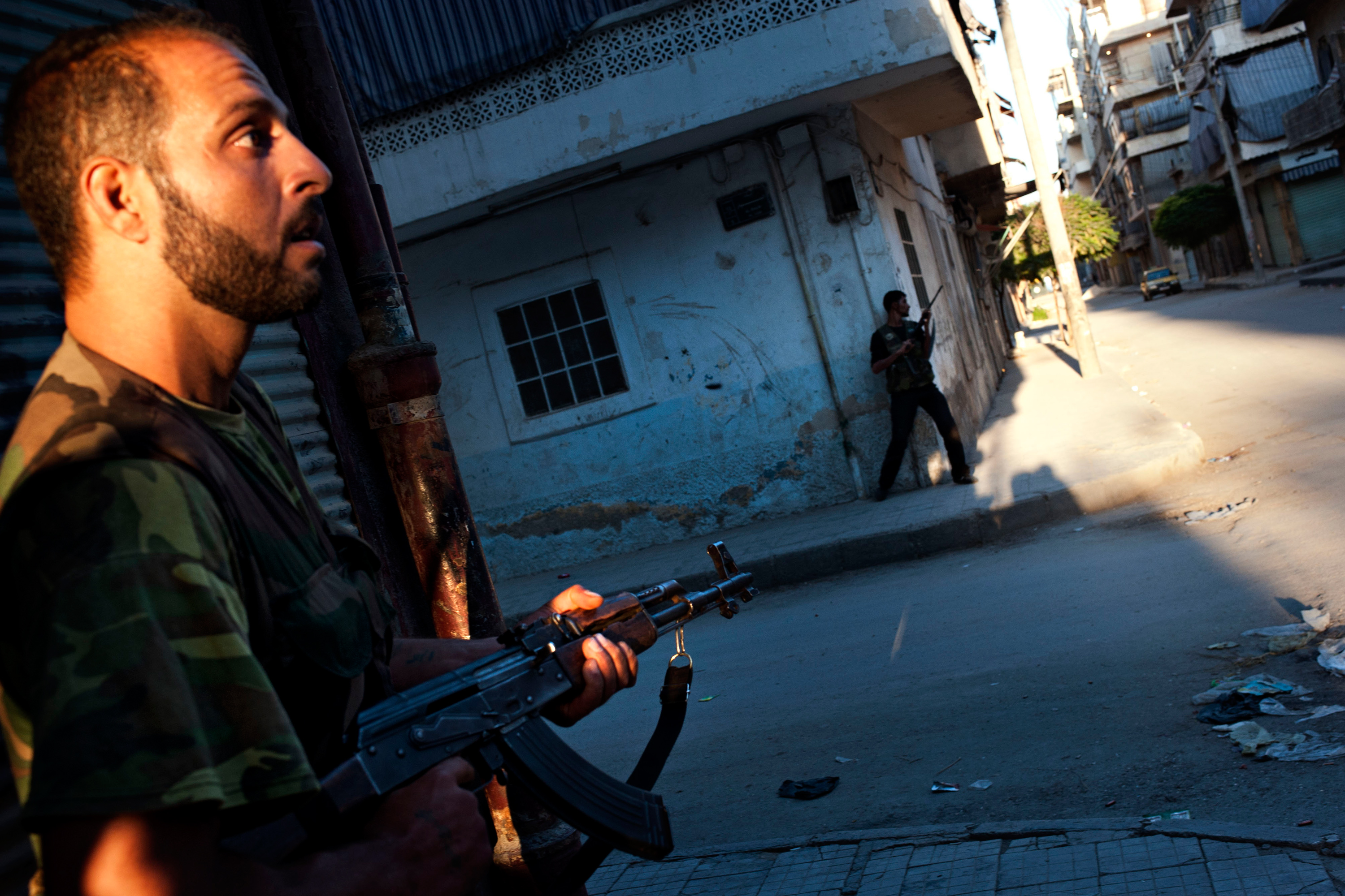 Free Syrian Army fighters take cover from helicopter fire in the Bustan Pasha neighborhood of Aleppo, Aug. 21.