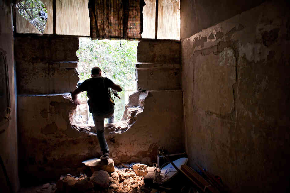 A Free Syrian Army fighter climbs through a damaged wall during fighting in the Saif Dawla neighborhood of Aleppo, Aug. 24.