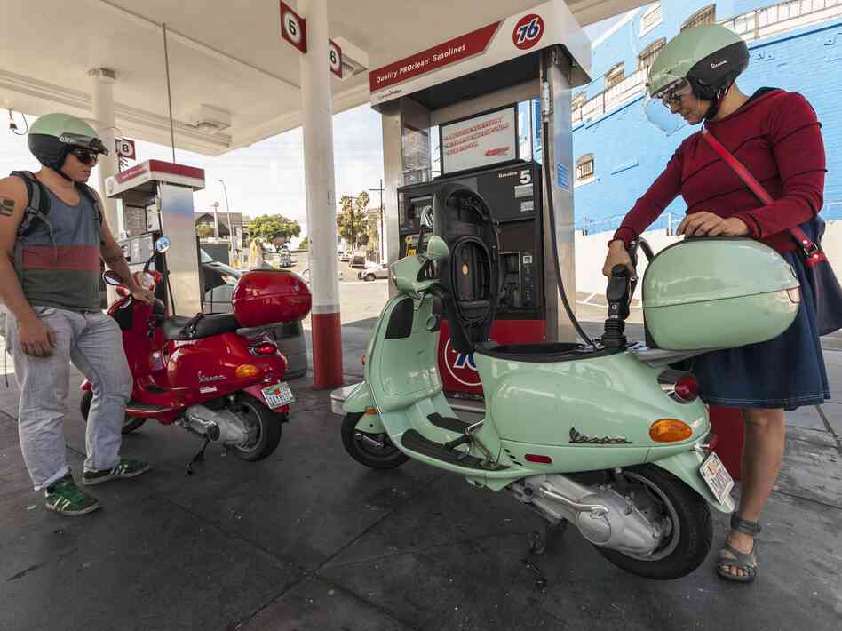 Motorcyclists Hanna Gilan, right, and her son Chaim Gilan fill up their Vespa scooters with less than two gallons at a gas station in the Echo Park district of Los Angeles on Oct. 4, 2012.