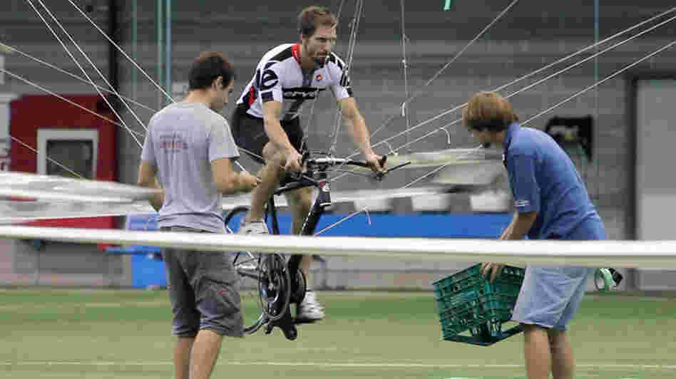 Todd Reichert pedals Atlas into the air, as Cameron Robertson (left) and team member Calvin Moes watch from the ground. Todd Reichert pedals Atlas into the air, as Cameron Robertson (left) and team member Calvin Moes watch from the ground.