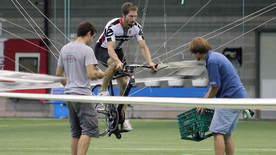 Todd Reichert pedals Atlas into the air, as Cameron Robertson (left) and team member Calvin Moes watch from the ground. Todd Reichert pedals Atlas into the air, as Cameron Robertson (left) and team member Calvin Moes watch from the ground.