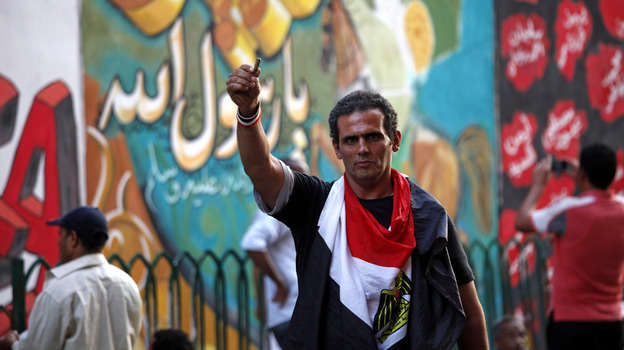 An Egyptian man waves a bullet casing in front of a mural that was painted on a recently whitewashed wall in Tahrir Square in Cairo.