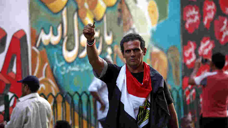 An Egyptian man waves a bullet casing in front of a mural that was painted on a recently whitewashed wall in Tahrir Square in Cairo.