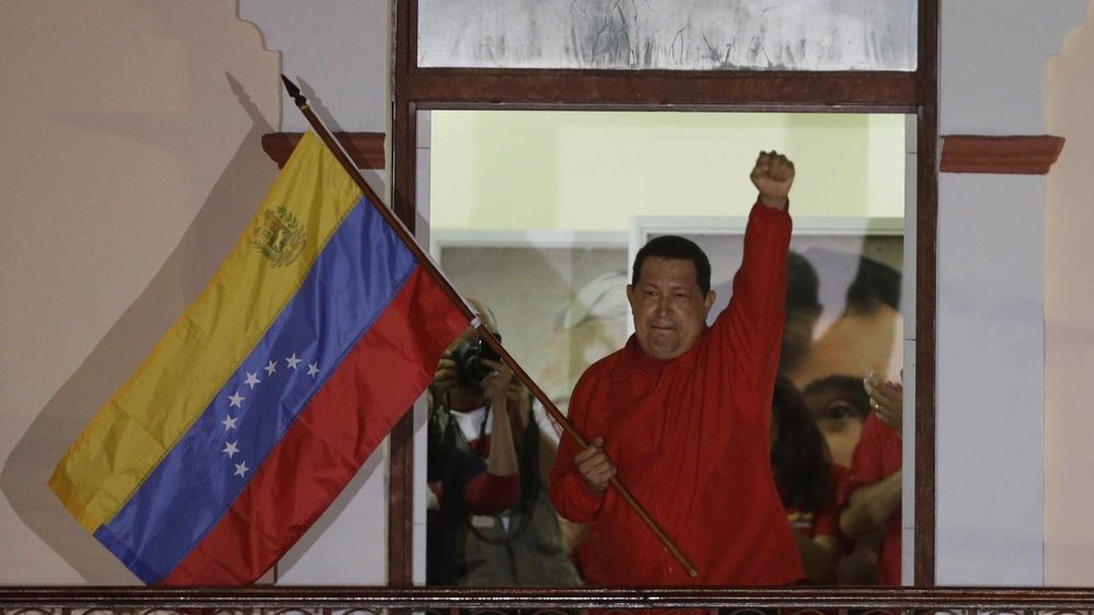 President Hugo Chavez waves a Venezuelan flag as he greets supporters at the Miraflores presidential palace balcony in Caracas on Sunday. Chavez won re-election and a new endorsement of his socialist project Sunday, surviving his closest race yet after a bitter campaign against opposition candidate Henrique Capriles.