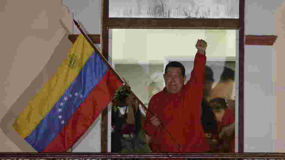 President Hugo Chavez waves a Venezuelan flag as he greets supporters at the Miraflores presidential palace balcony in Caracas on Sunday. Chavez won re-election and a new endorsement of his socialist project Sunday, surviving his closest race yet after a bitter campaign against opposition candidate Henrique Capriles.