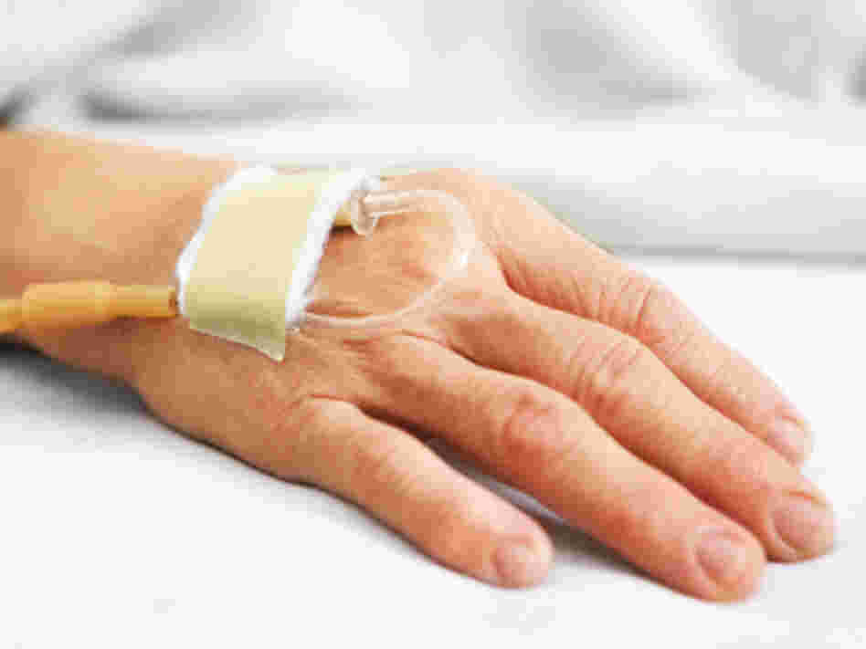 A woman's hand with an IV in a hospital bed. A woman's hand with an IV in a hospital bed.
