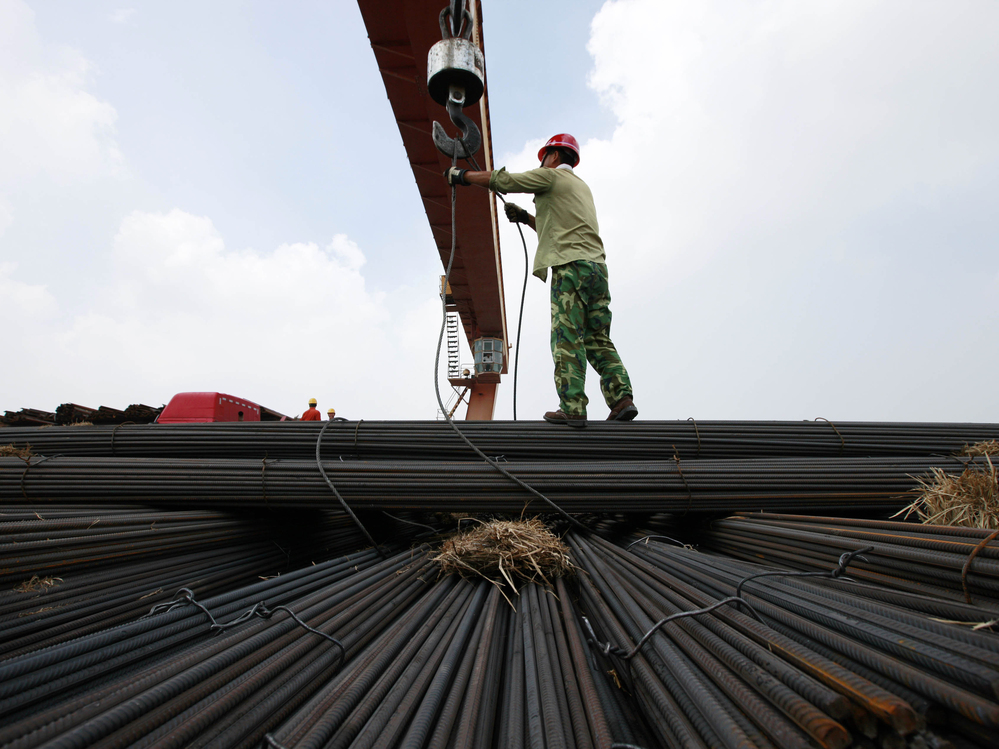 In China's Anhui province, a worker unloads steel bars at a factory. A slowdown in China and other major nations threatens to pull the global economy into recession, the International Monetary Fund warns.