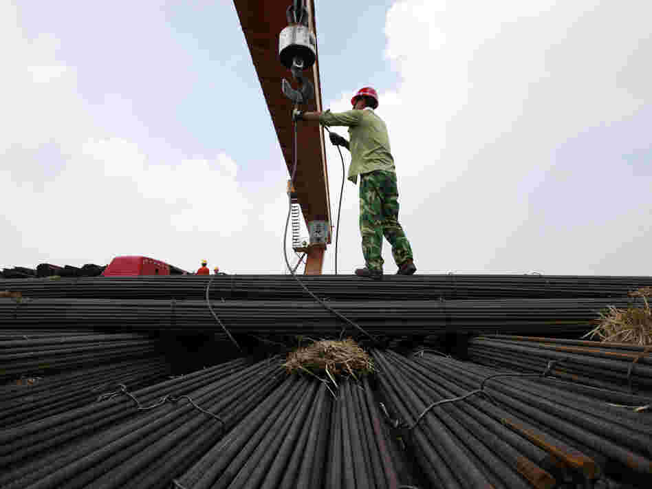In China's Anhui province, a worker unloads steel bars at a factory. A slowdown in China and other major nations threatens to pull the global economy into recession, the International Monetary Fund warns.