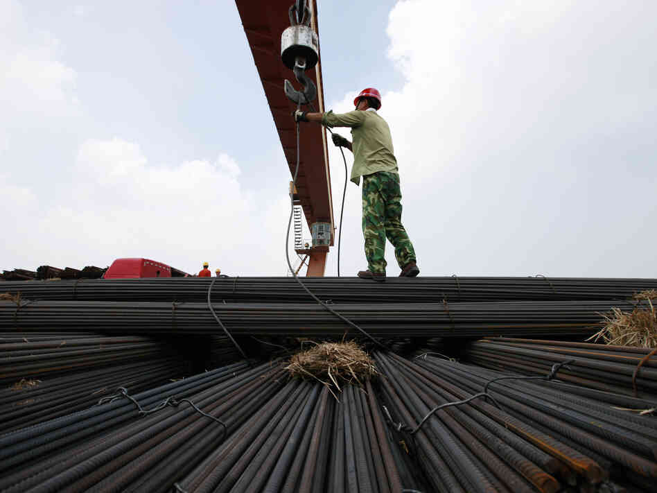 In China's Anhui province, a worker unloads steel bars at a factory. A slowdown in China and other major nations threatens to pull the global economy into recession, the International Monetary Fund warns.