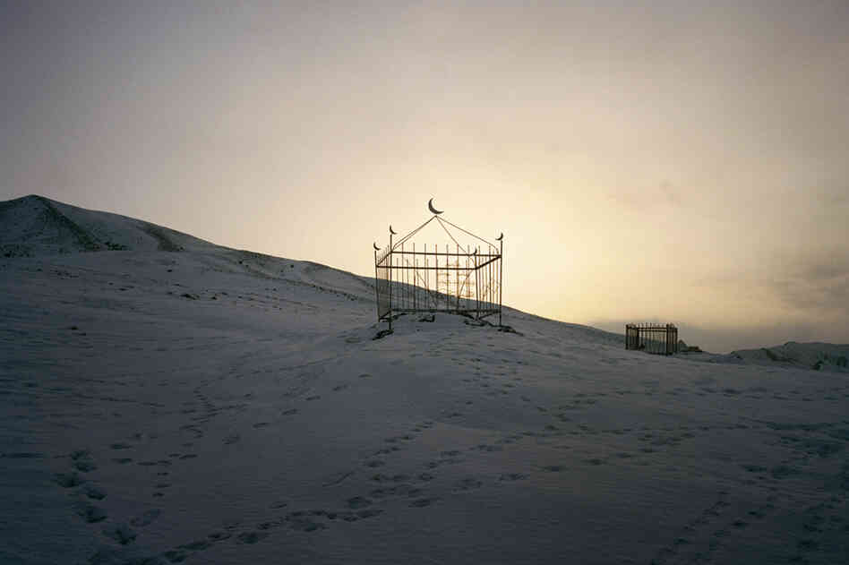 A Kyrgyz grave is seen on a hillside slope near the Kuruman family's village. The Kuruman parents, retired from the nomadic life, stay in a village of mud-and-thatch houses with a small herd of livestock.