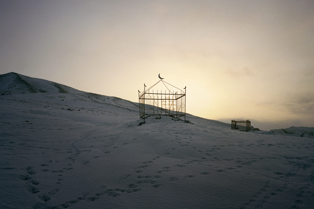 A Kyrgyz grave is seen on a hillside slope near the Kuruman family's village. The Kuruman parents, retired from the nomadic life, stay in a village of mud-and-thatch houses with a small herd of livestock.