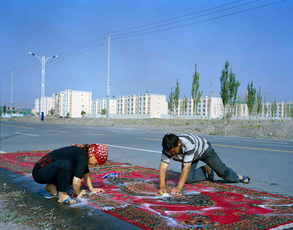 Relatives of the Kuruman family wash carpets by hand. In the background is Wuqiaxian, a growing town along the planned highway. According to Takayama, many of the traditional mud-and-thatch houses will be demolished, and the communities will become more fixed in an urbanizing town.
