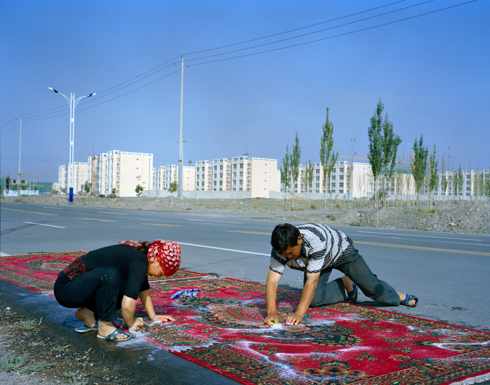 Relatives of the Kuruman family wash carpets by hand. In the background is Wuqiaxian, a growing town along the planned highway. According to Takayama, many of the traditional mud-and-thatch houses will be demolished, and the communities will become more fixed in an urbanizing town.