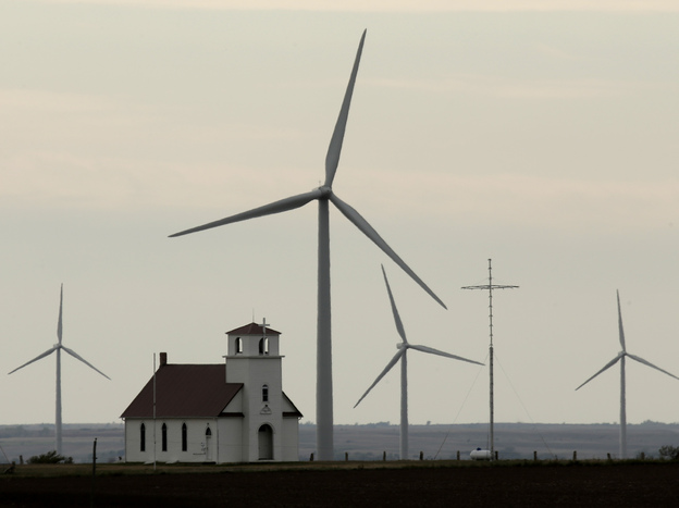 Wind turbines dwarf a church near Wilson, Kan. The White House wants to extend a federal wind energy credit, but the Romney campaign wants to let it expire.