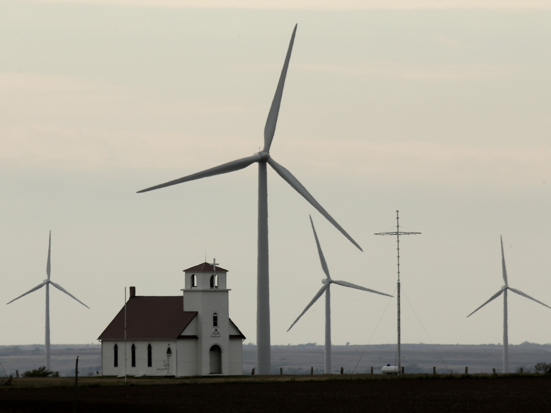 Wind turbines dwarf a church near Wilson, Kan. The White House wants to extend a federal wind energy credit, but the Romney campaign wants to let it expire.