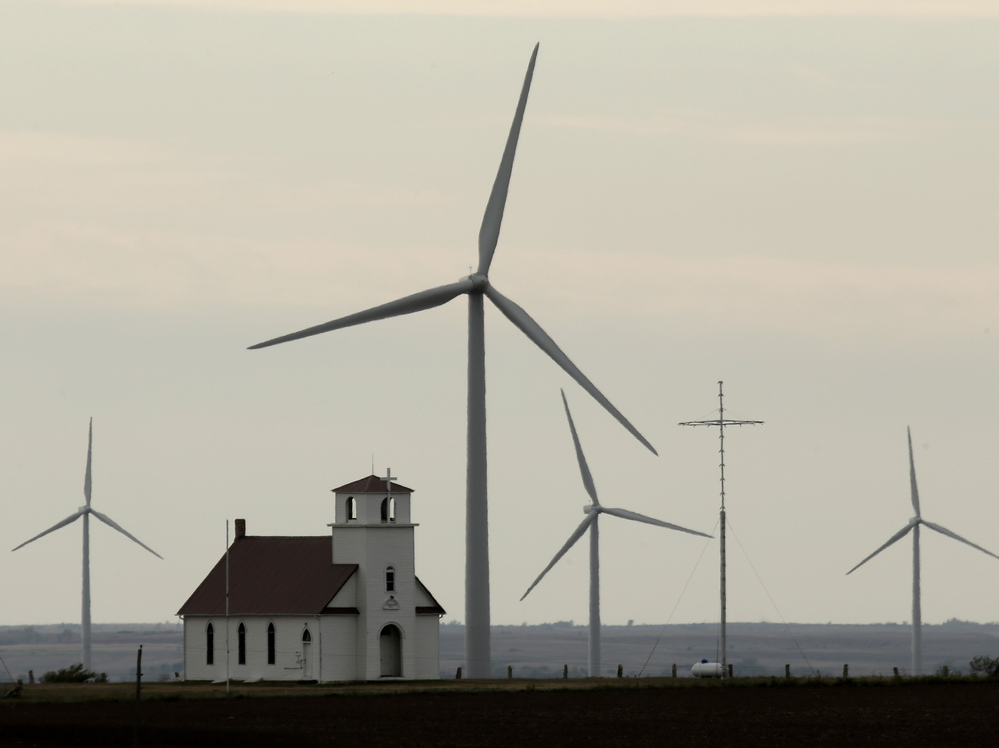 Wind turbines dwarf a church near Wilson, Kan. The White House wants to extend a federal wind energy credit, but the Romney campaign wants to let it expire.
