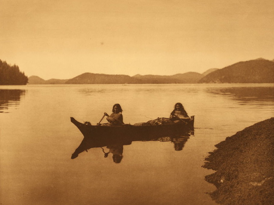 "Two Hesquiat women," reads the Curtis caption, "are homeward bound with the product of their day's labor in gathering food, and cedar-bark to be used in making mats."