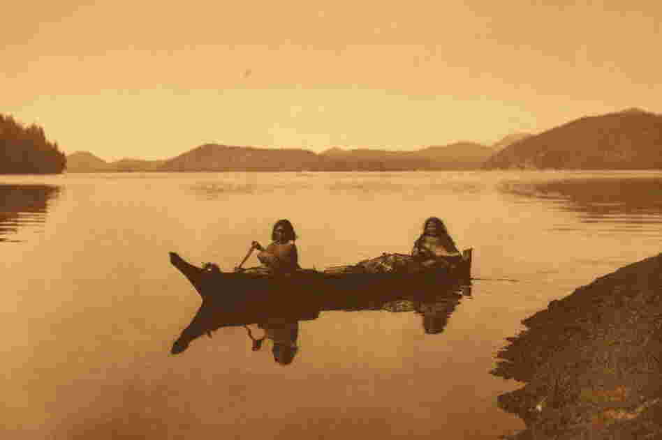 "Two Hesquiat women," reads the Curtis caption, "are homeward bound with the product of their day's labor in gathering food, and cedar-bark to be used in making mats."
