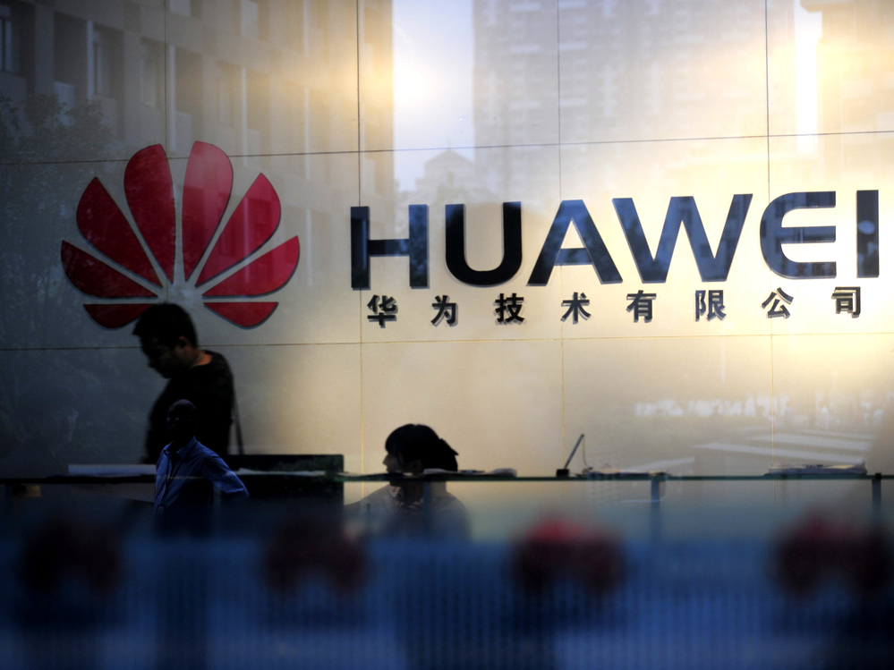 Staff and visitors walk past the lobby at the Huawei office in Wuhan, China. Beijing has urged Washington to "set aside prejudices" after a draft congressional report said Chinese telecom firms Huawei and ZTE were security threats that should be banned from business in the U.S.