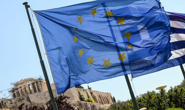European Union flag and Greek flag wave in front of the Acropolis, in central Athens.