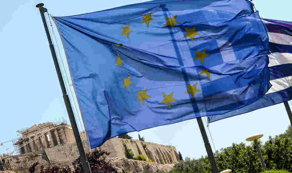 European Union flag and Greek flag wave in front of the Acropolis, in central Athens.