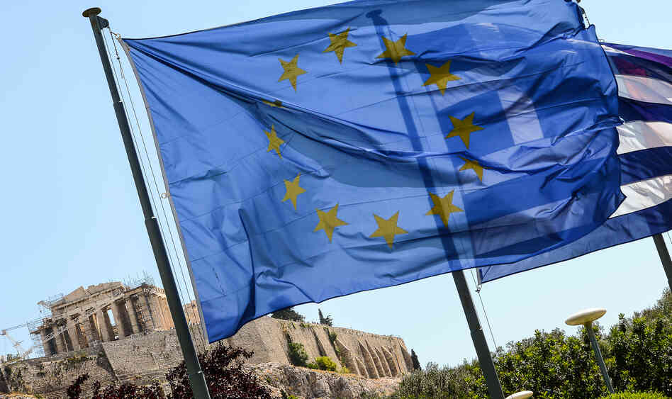 European Union flag and Greek flag wave in front of the Acropolis, in central Athens.