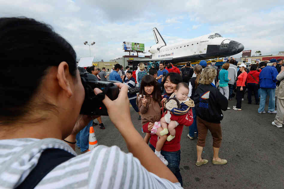 Mifumi Nakajima takes a picture of her husband Nozomo Nakajima holding their children Leigha Nakajima, 3, and Eli Nakajima, 6 months, in front of the space shuttle Endeavour parked in a mall parking lot.