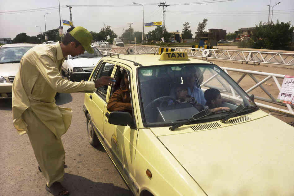 Khan Wali, 21, scrutinizes passing cars for young children at the traffic checkpoint. If a child appears to be younger than 5, the driver must pull over.