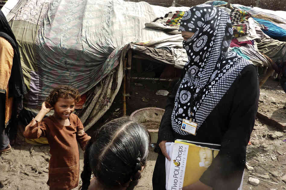Social mobilizers like Awaiz Amjad (right) walk through dense slums and go door to door inoculating children. Many children are malnourished, with weak immune systems.