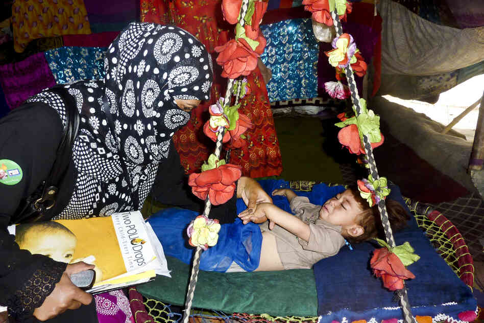 Amjad checks a child's fingernail to see whether he has been inoculated in a Lahore slum. It can be dangerous work: Some vaccinators have been attacked, and one was killed in a Karachi slum this summer.
