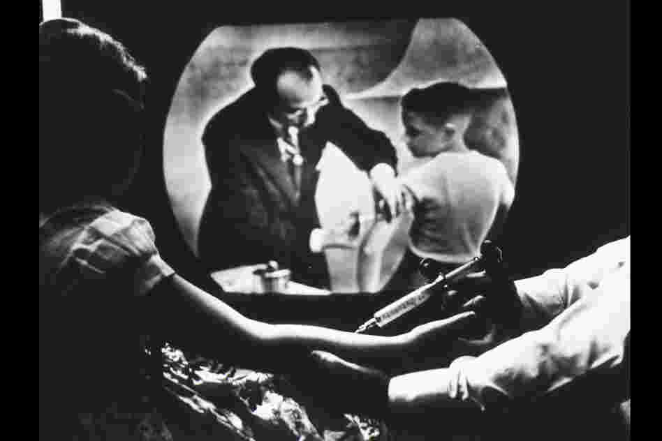 While receiving a polio vaccine, Cheryl Halpin watches Salk inoculate another child on television.