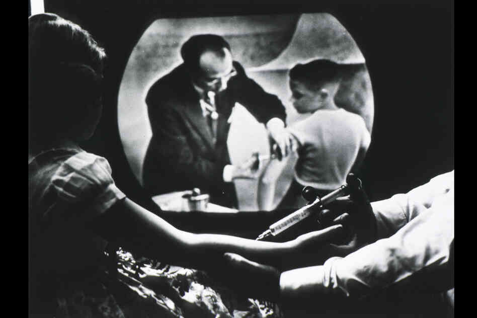 While receiving a polio vaccine, Cheryl Halpin watches Salk inoculate another child on television.