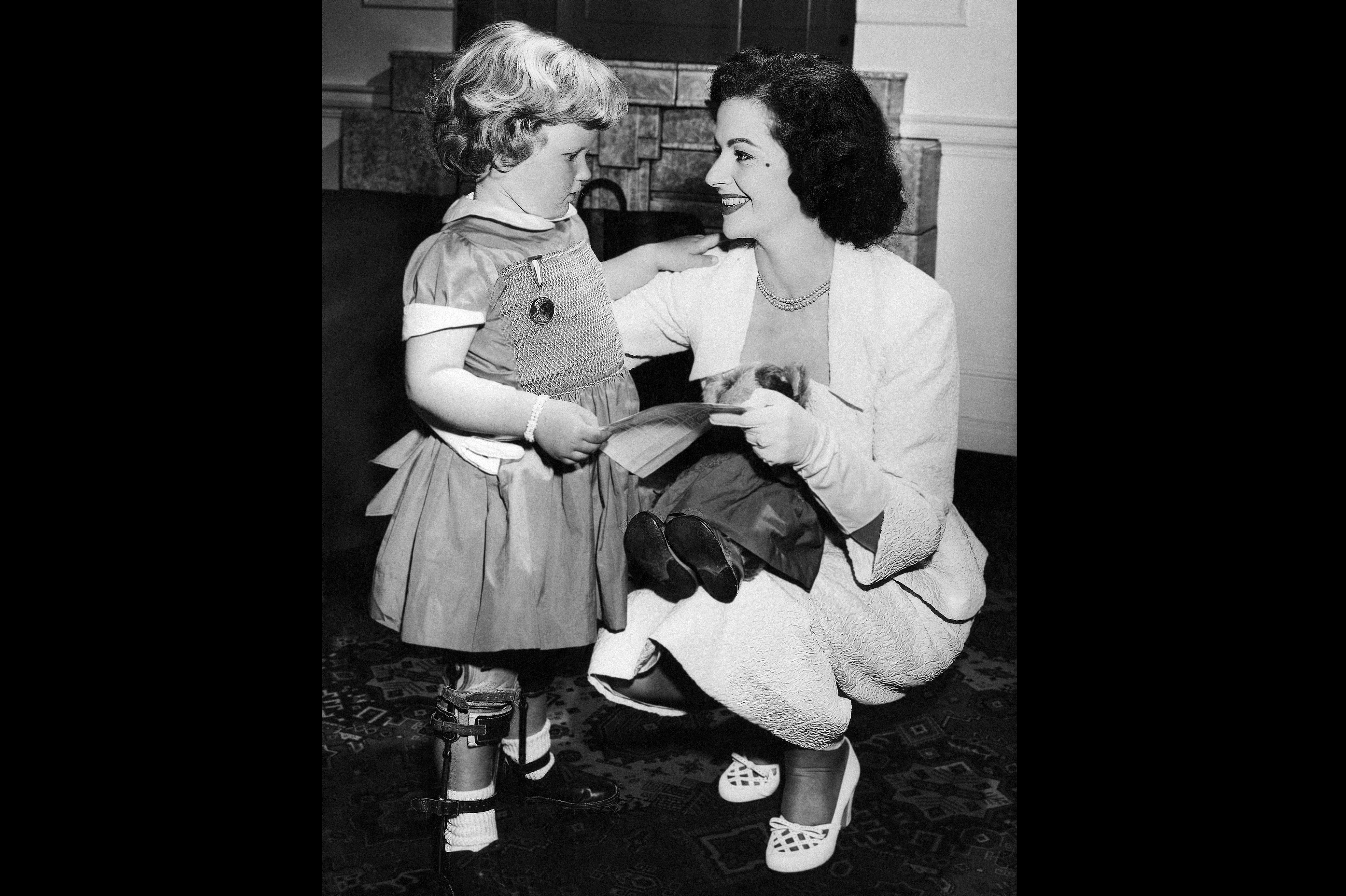 Many celebrities and actresses helped to promote the fight against polio. In this image from 1953, the British actress Margaret Lockwood makes friends with a young polio survivor, Mary Burton, 4, as they buy stamps to support polio research and treatment. Many celebrities and actresses helped to promote the fight against polio. In this image from 1953, the British actress Margaret Lockwood makes friends with a young polio survivor, Mary Burton, 4, as they buy stamps to support polio research and treatment.
