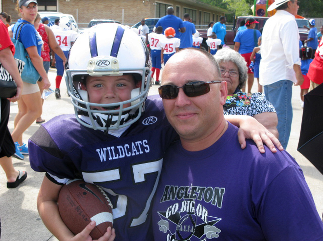 Bryce Rolan, 8, and his dad, Wesley, at a Wildcat game in Angleton, Texas. At 4 feet 2 inches and 65 pounds, Bryce is playing his first year of tackle football.