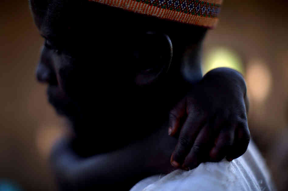 Adamu Ali carries his 4-year-old son, Omar, who was stricken with polio earlier this year. They live in the village of Minjibir.