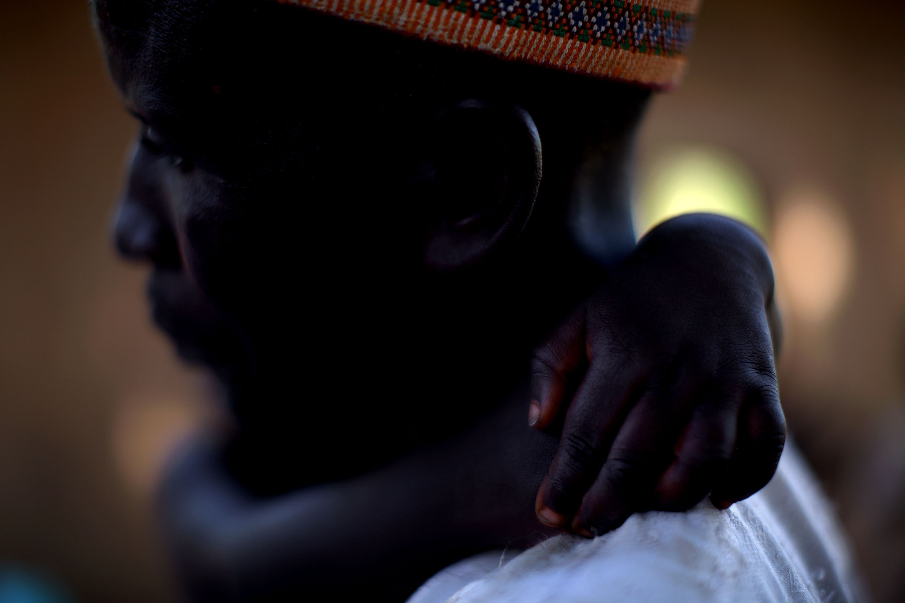 Adamu Ali carries his 4-year-old son, Omar, who was stricken with polio earlier this year. They live in the village of Minjibir.