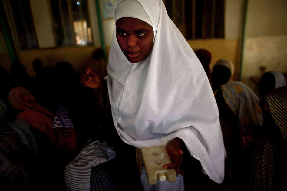 Sahya Idriss, a service provider at the health clinic in Minjibir, carries a vial of the polio vaccine.