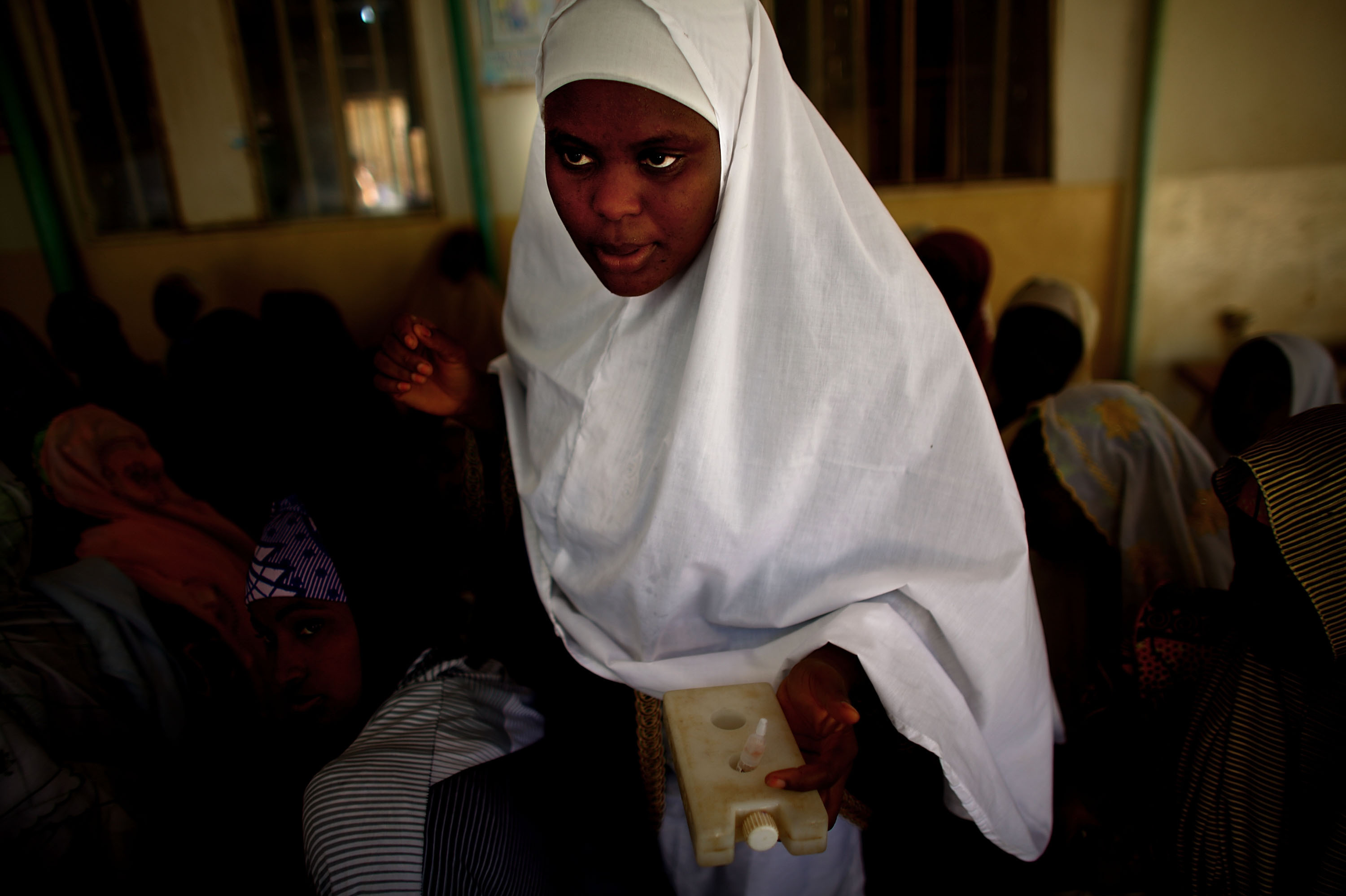 Sahya Idriss, a service provider at the health clinic in Minjibir, carries a vial of the polio vaccine.