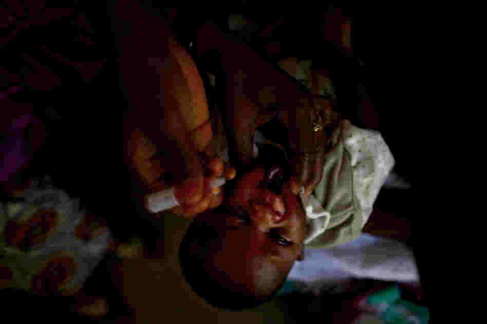A child is vaccinated against polio at the Minjibir health clinic. The procedure, in which two drops of vaccine are pinched into a child's mouth, only takes a few seconds. Children should get at least three doses of the vaccine, spread out over time.