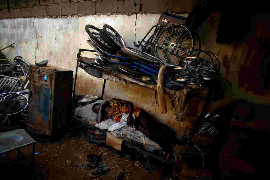 A man naps at a scooter and tricycle shop run by polio victims in Kano.