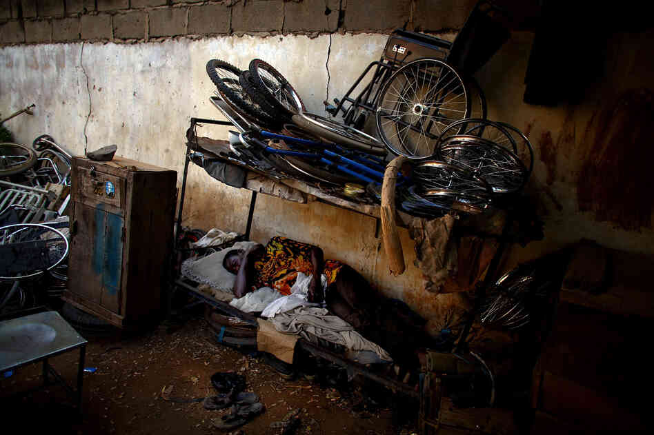 A man naps at a scooter and tricycle shop run by polio victims in Kano.