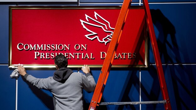 A worker cleans a sign before Tuesday's presidential debate at Hofstra University in Hempstead, N.Y.