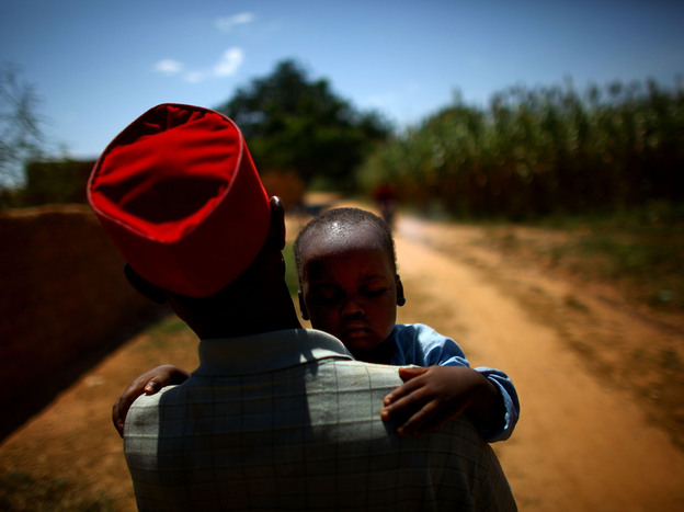 Ado Ibrahim carries his son Aminu through a village in northern Nigeria. Aminu was paralyzed by polio in August.